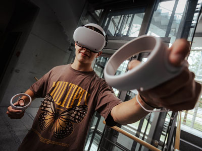 Junge mit VR-Brille streckt Bedienelemente nach Vorne